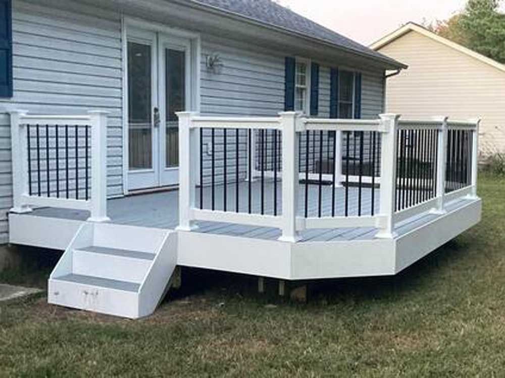 White elevated deck with railings and steps attached to a gray house