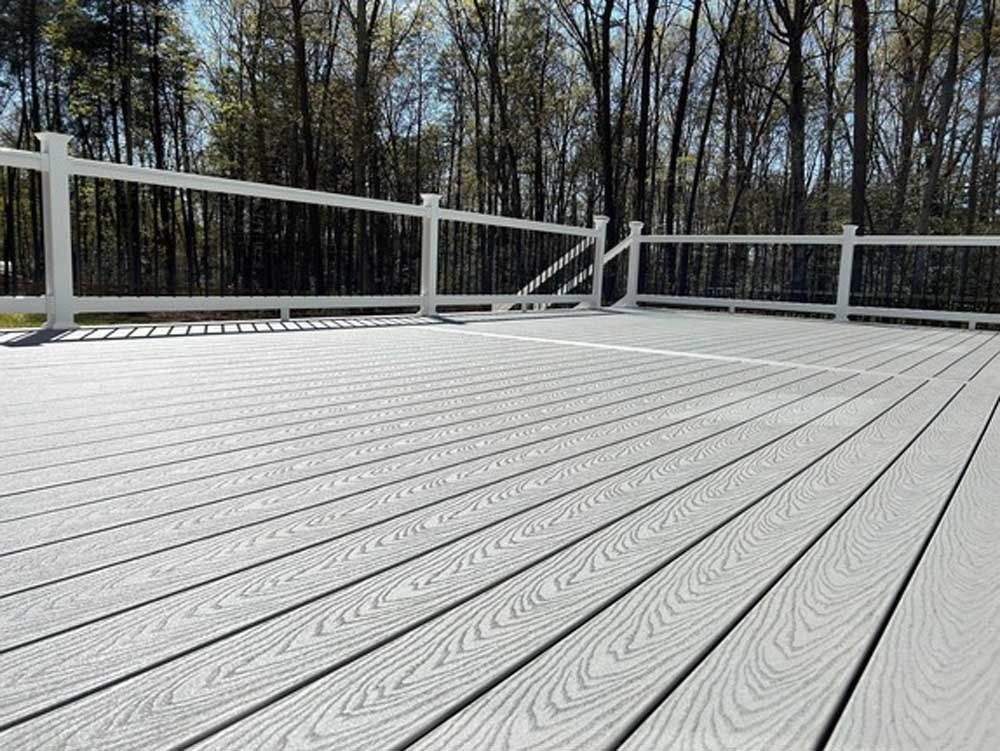 White wooden deck overlooking trees and a wooded backdrop