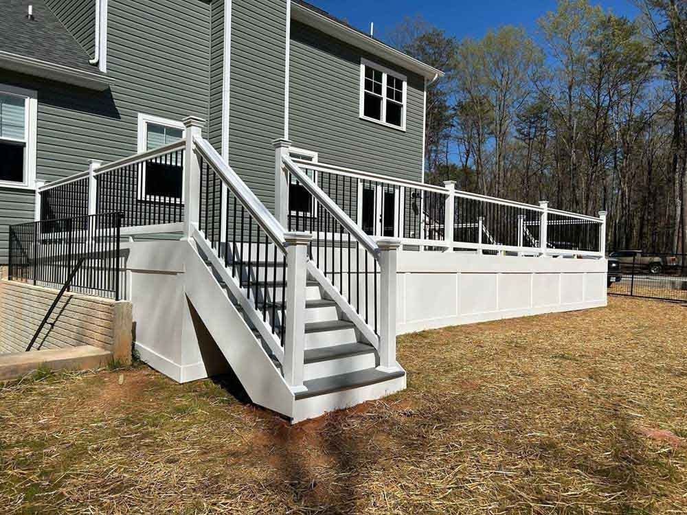 House exterior with white ramp and stairs leading to a deck on a grassy yard
