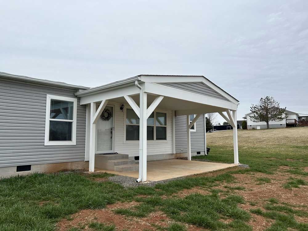 Mobile home exterior with a small covered porch and white posts on a grassy lot