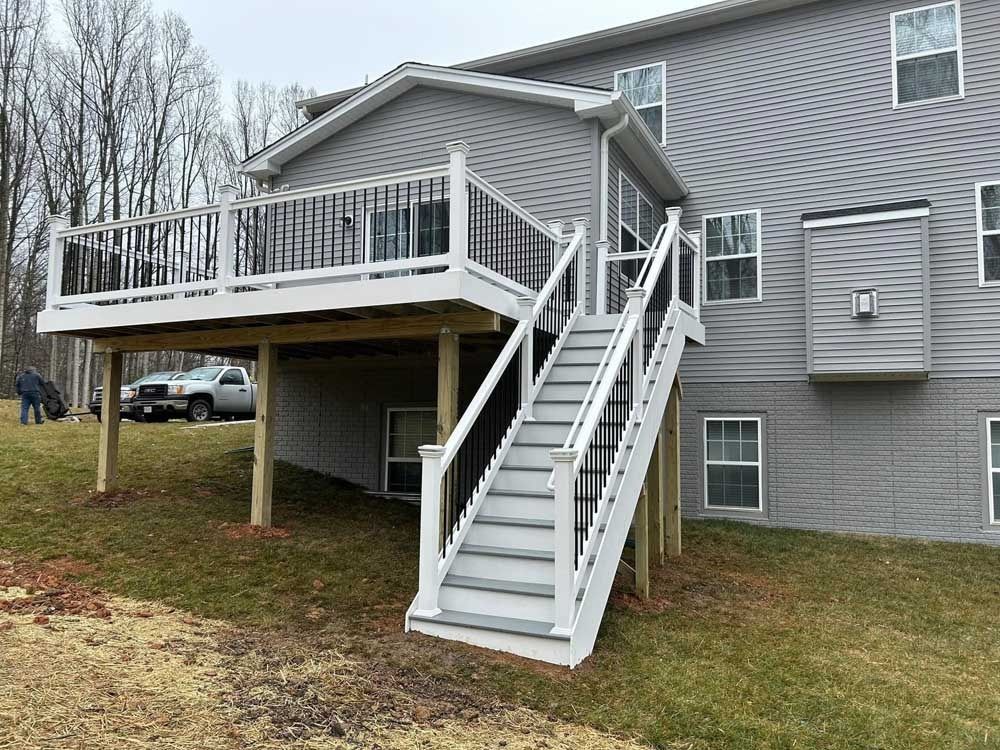 Raised deck and white staircase on the side of a gray house