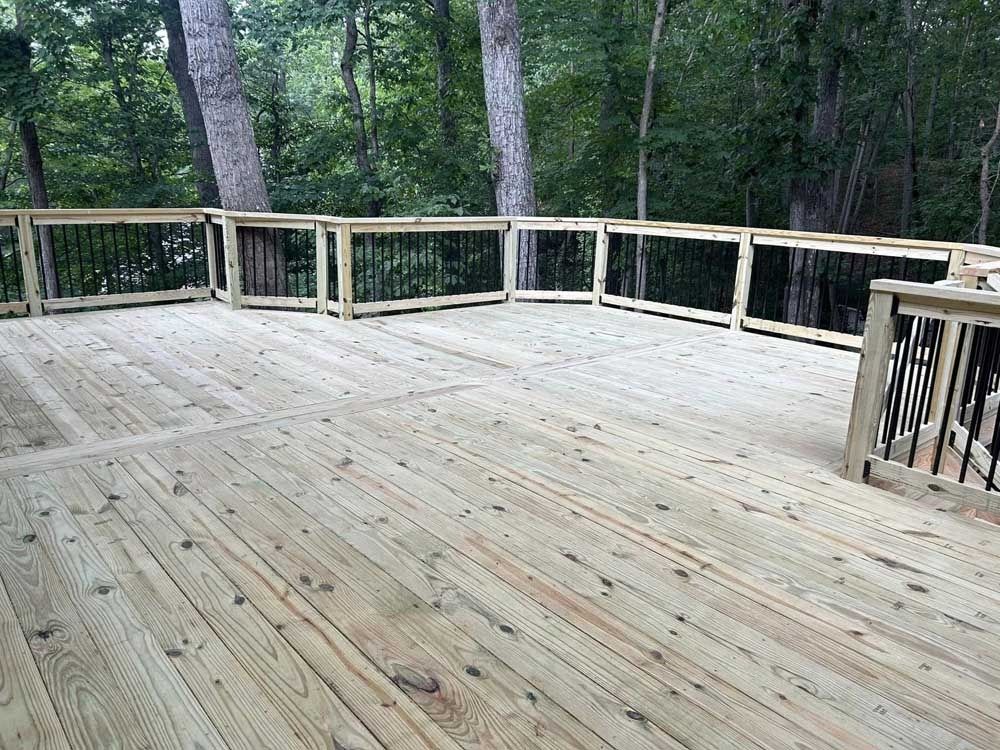 Wooden deck overlooking a wooded area, with railings and forest trees in the background.