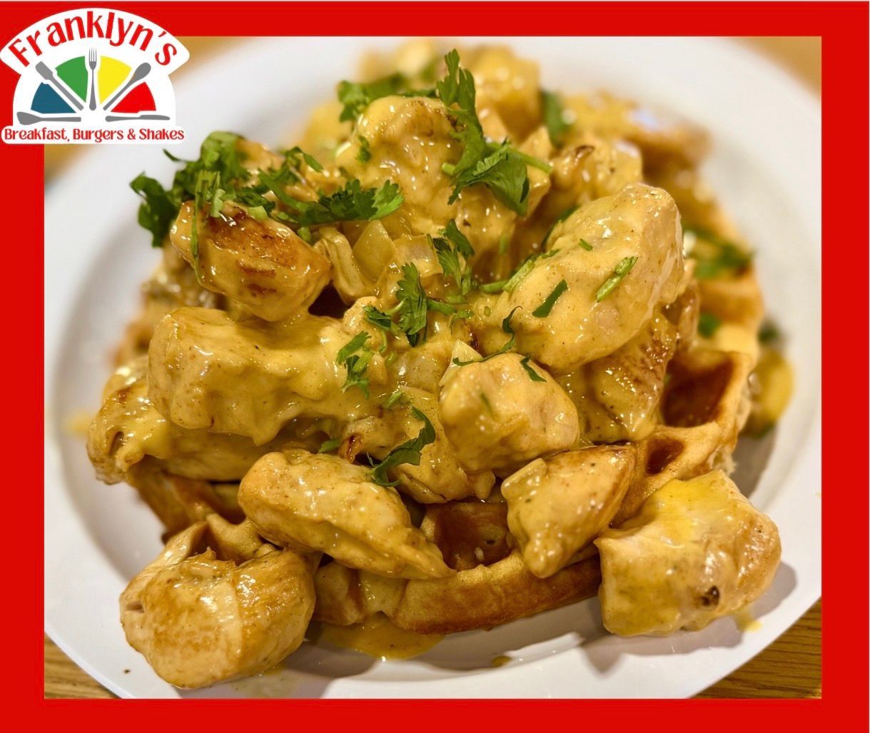 Creamy chicken and herbs piled on a white plate with a red restaurant border and logo