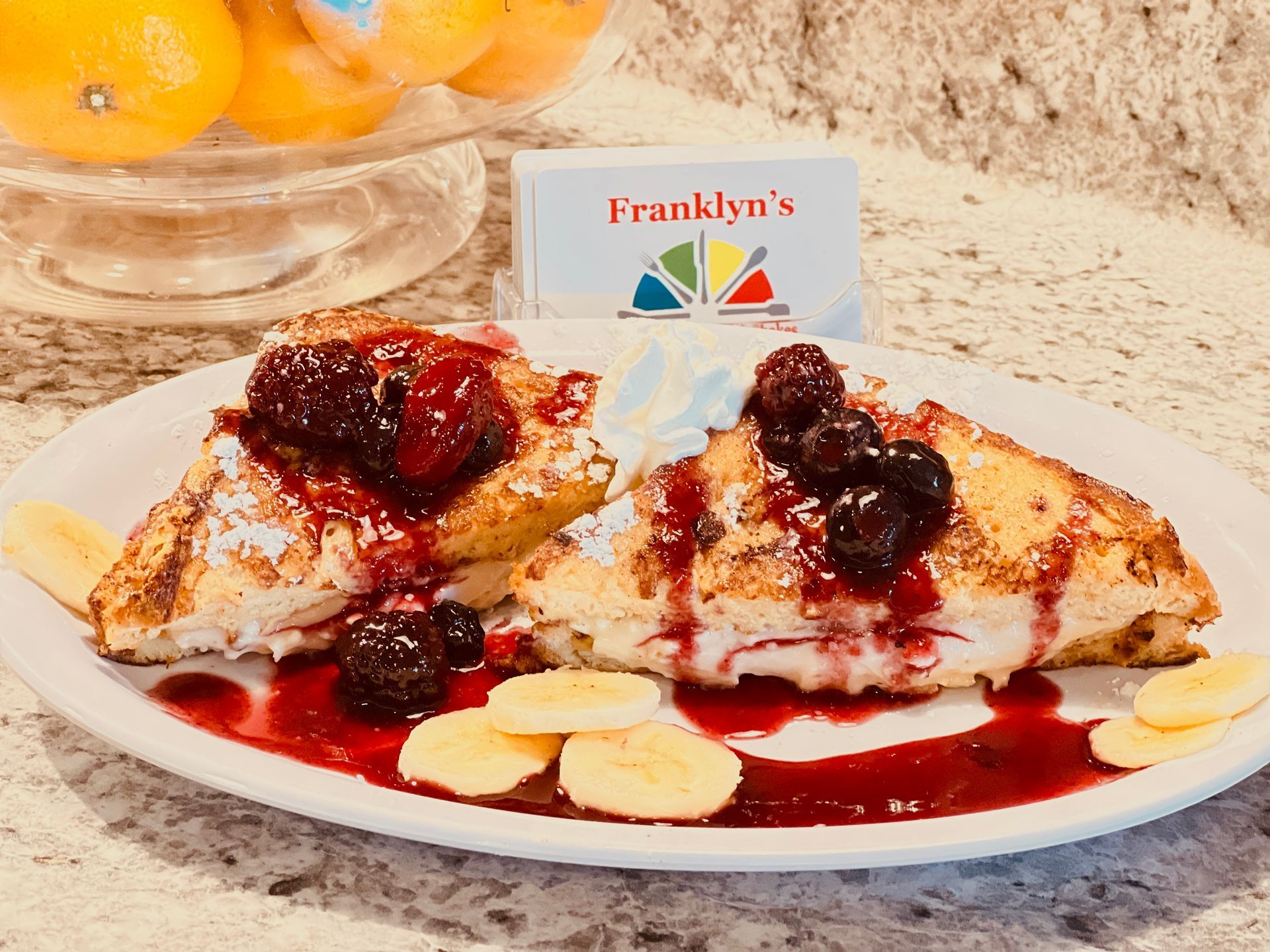 Dessert crepes topped with berries and powdered sugar on a plate in a café setting