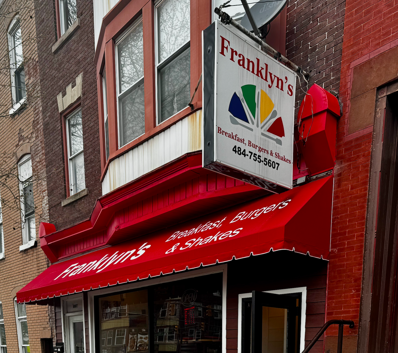 Red storefront with red awning and hanging sign for Franklin’s on a brick building
