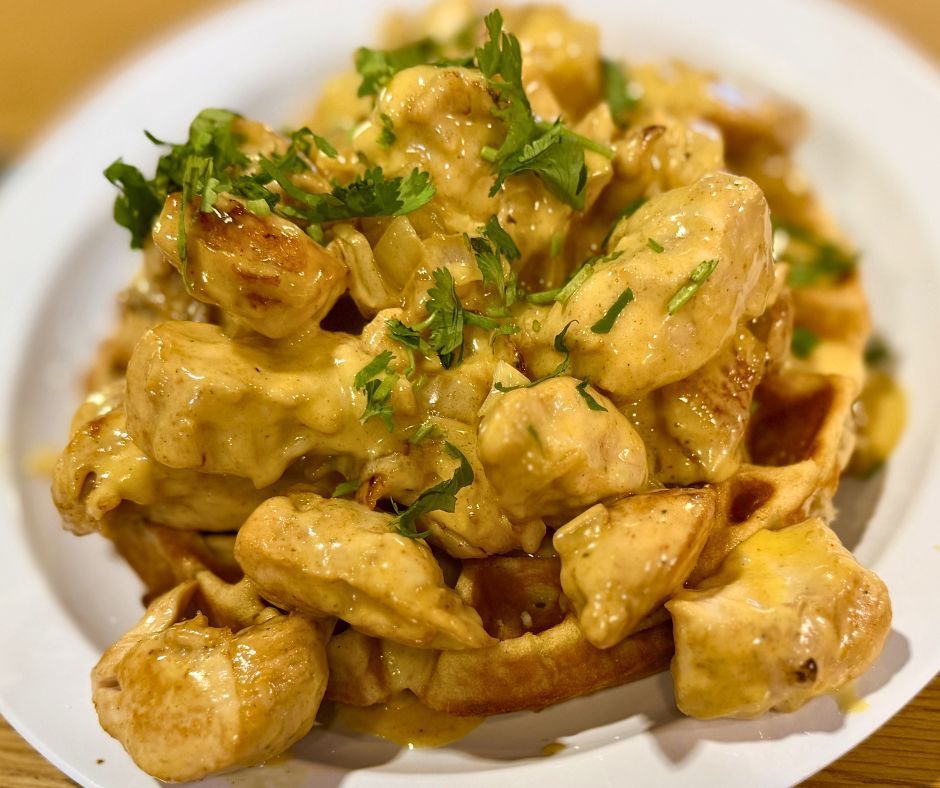 Creamy chicken and potato dish topped with chopped parsley on a white plate
