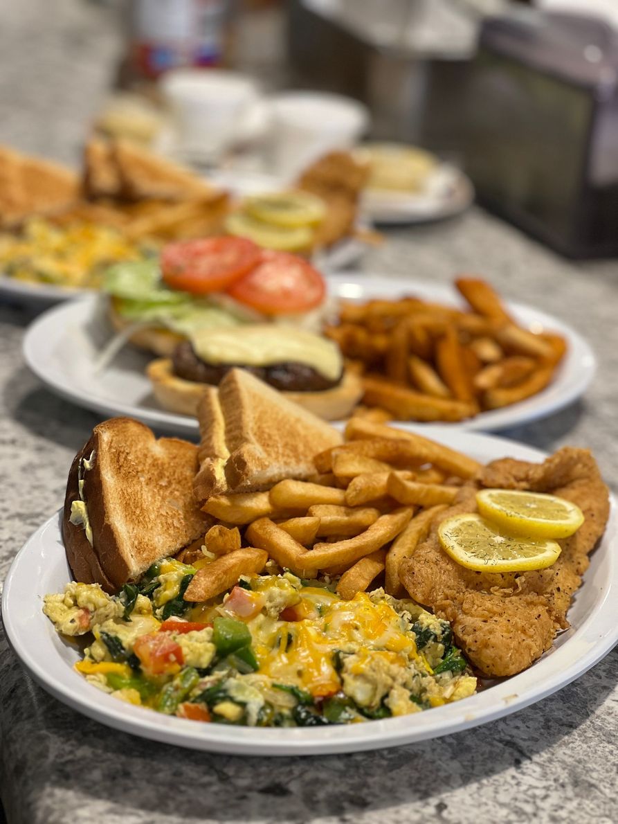 Plates of toast, fries, salad, and lemon-topped breaded cutlet on a granite table.