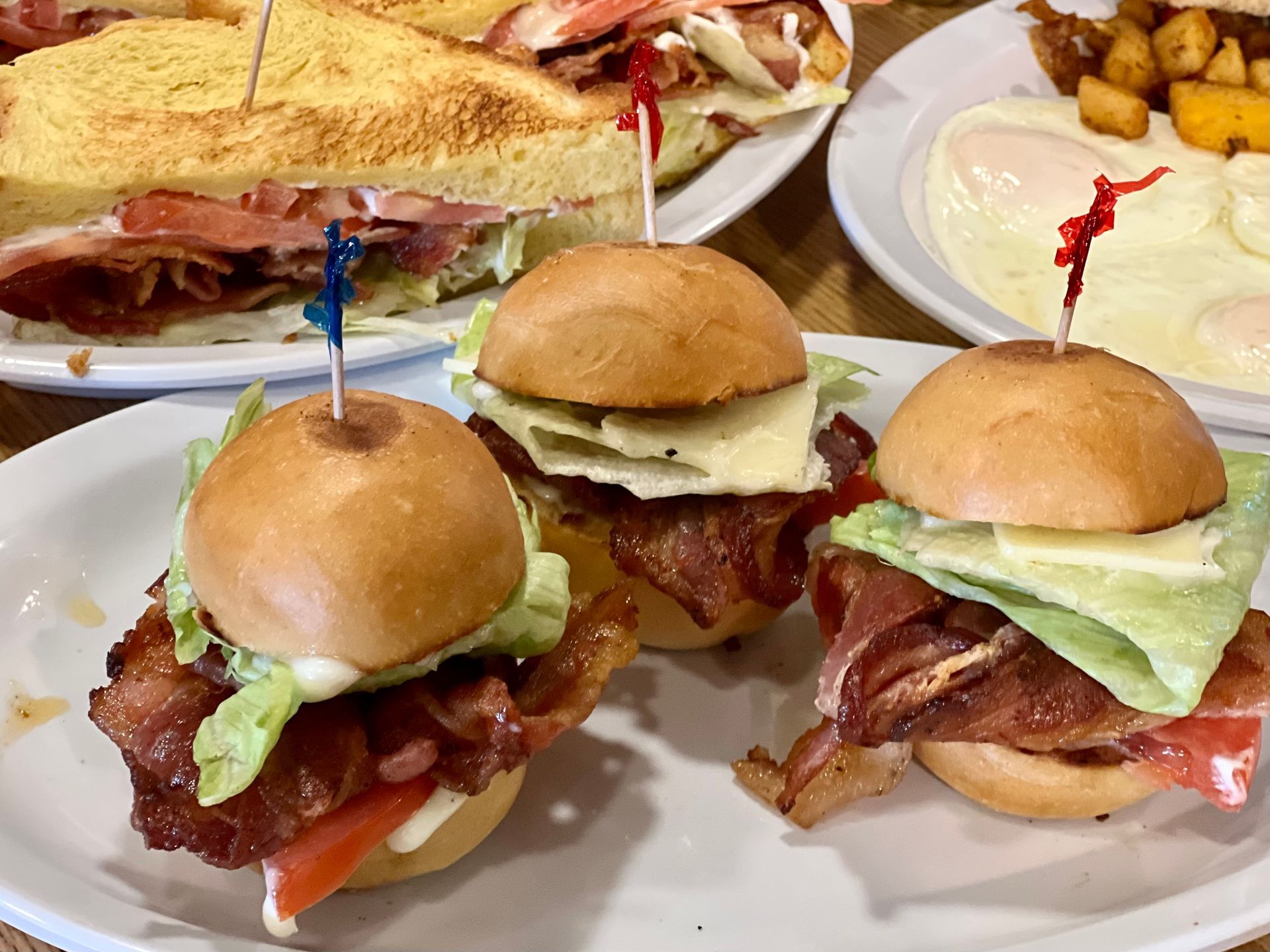 Assorted sandwiches and sliders on a table with chips and dipping sauce