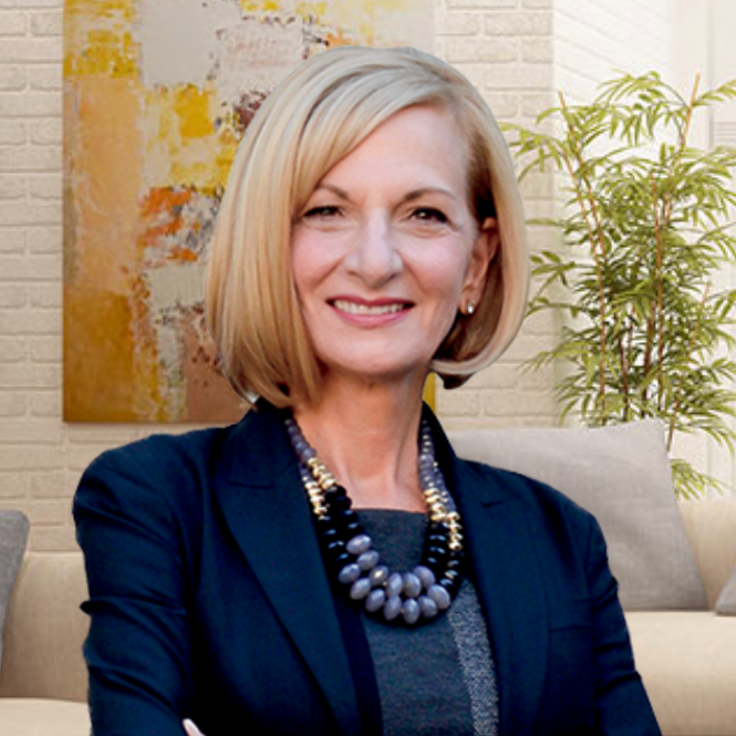 A woman wearing a blue jacket and a necklace is sitting on a couch