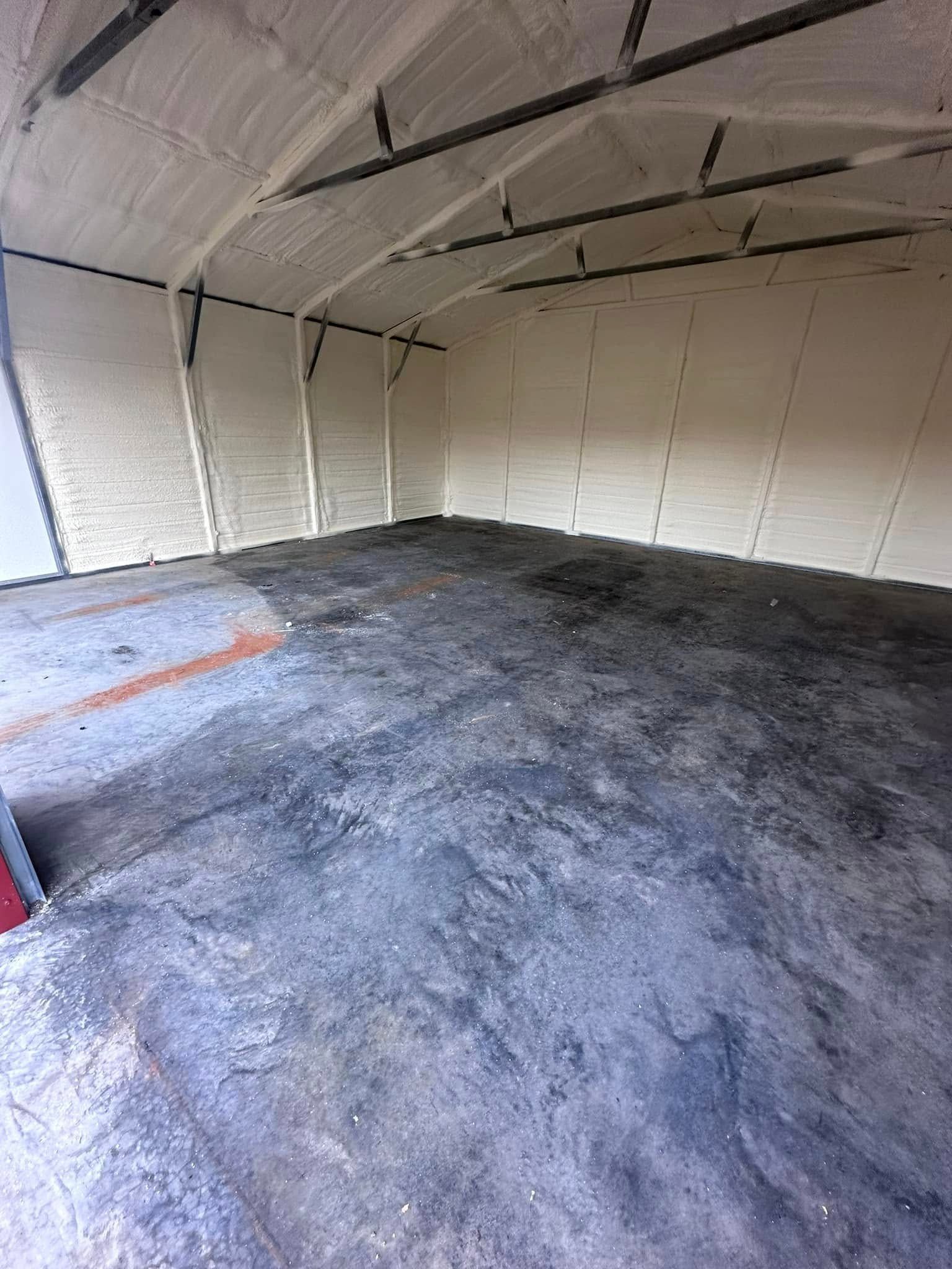 Empty garage interior with white walls, curved ceiling, and dark concrete floor