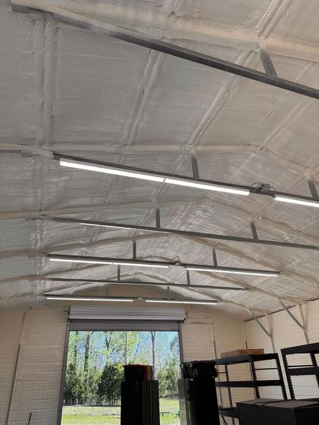 Interior of a garage with a white insulated ceiling, fluorescent lights, and shelves along the right wall