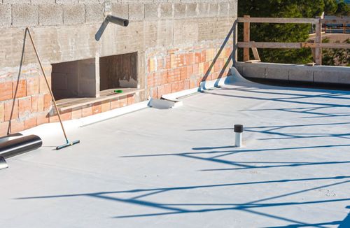 Flat white rooftop with vents, brick wall, and blue safety lines in bright sunlight