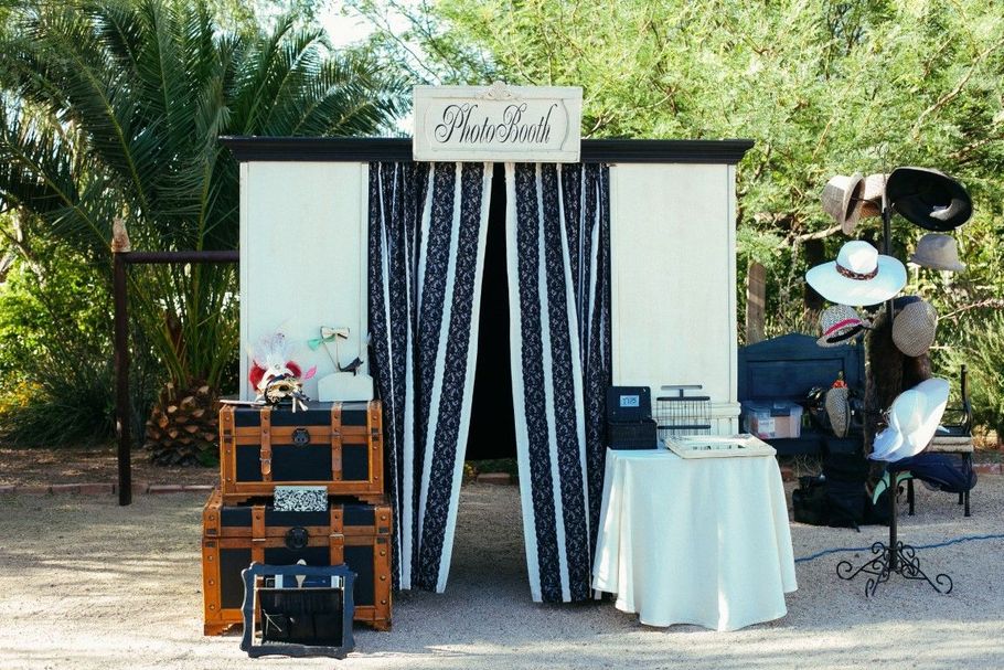 Outdoor booth with striped backdrop, small tables, and event decor among palm trees