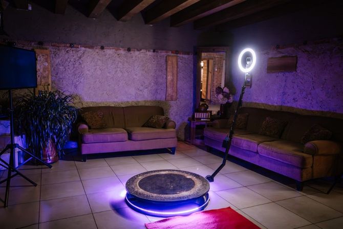 Purple-lit lounge with sofas, tiled floor, and a ring light beside a central circular platform