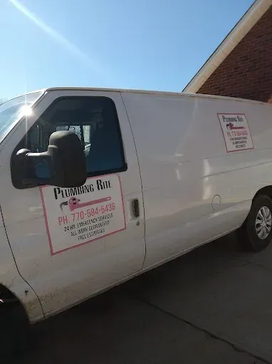 White work van with pink logo, parked near a building on a sunny day.