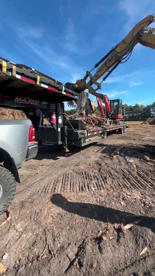 Construction site with excavator and dump truck on a dirt lot under a blue sky