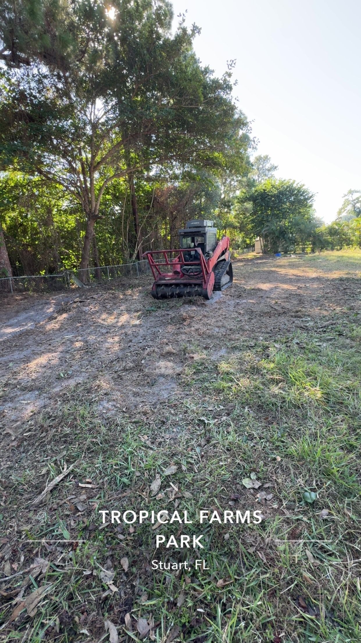 Small red tractor in a tree-lined farm field with “TROPICAL FARMS PARK” text at the bottom