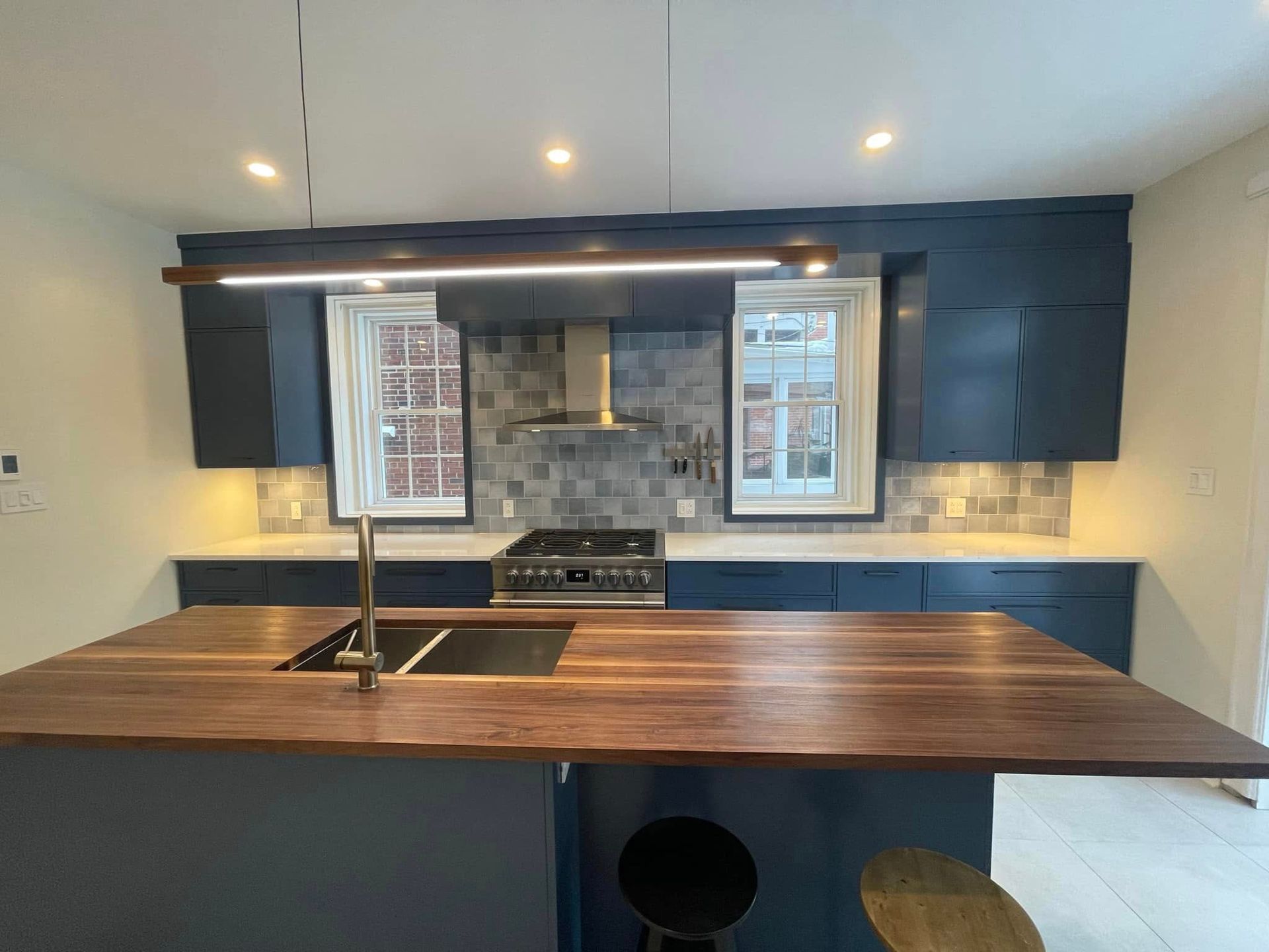 Cuisine moderne avec placards bleus, îlot en bois et appareils électroménagers en acier inoxydable.