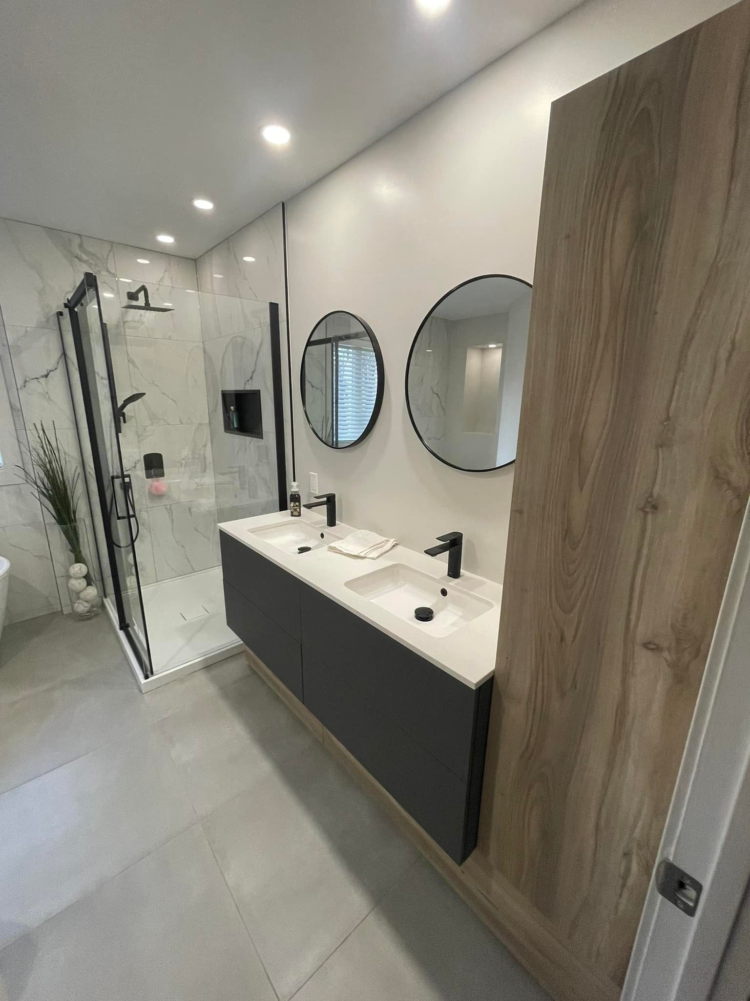 Salle de bains moderne avec meuble-lavabo double vasque, douche et deux miroirs ronds.