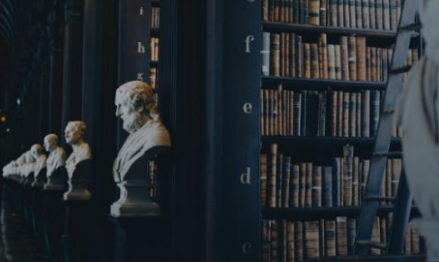 Rows of leather-bound books on polished wooden shelves in a warmly lit library.