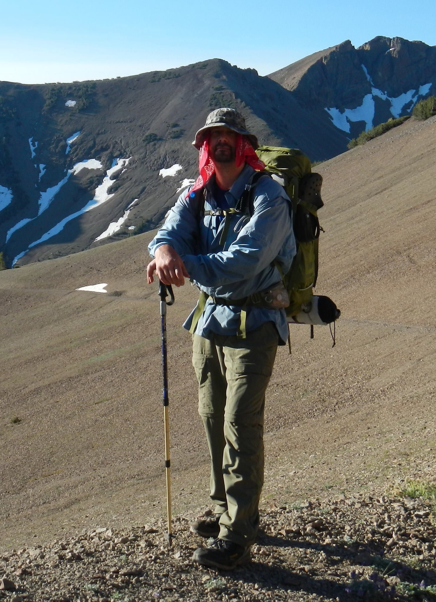 A man with a backpack is standing on a rocky hillside
