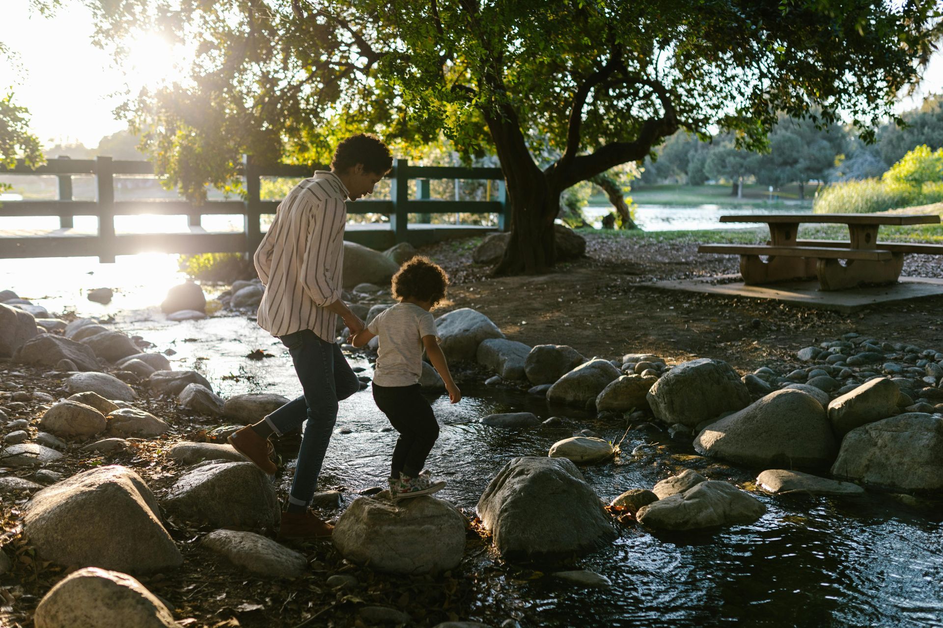 A woman and child are crossing a river on rocks.