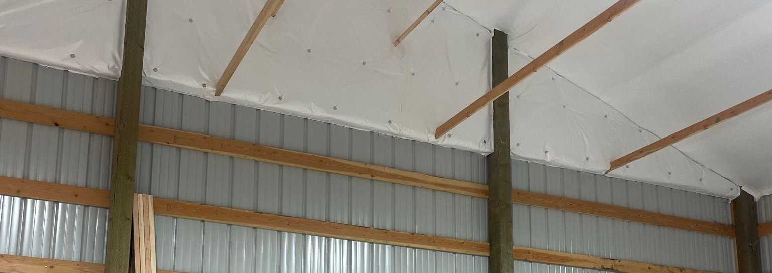Pole barn ceiling insulation with white vapor barrier installed in Spokane shop