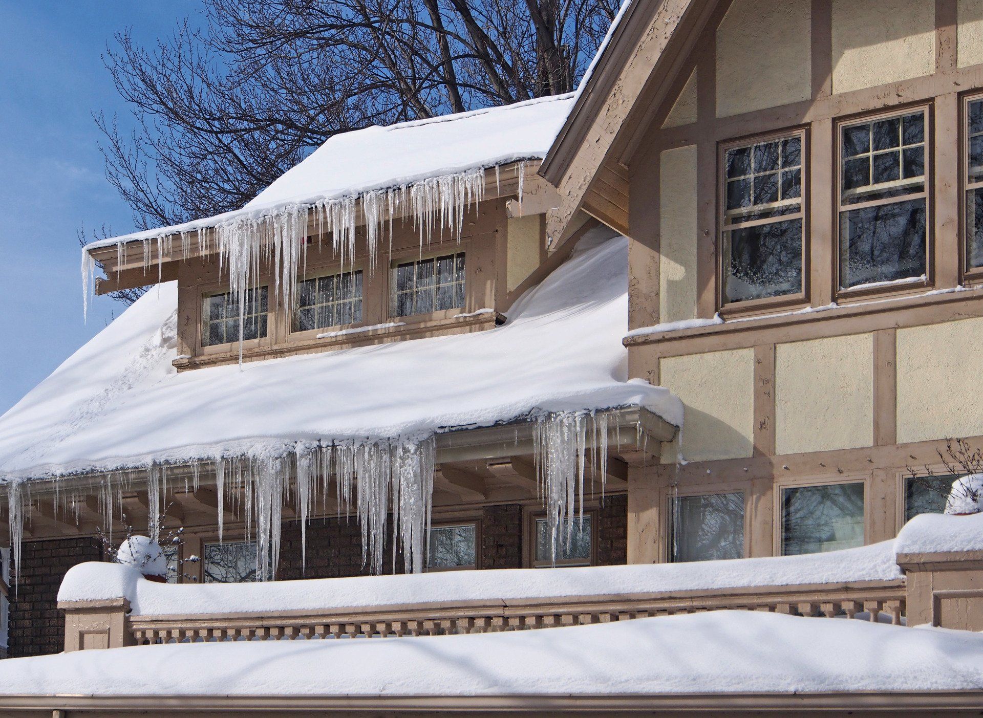 Large icicles and ice dams hanging from the roof of a Spokane home with poor attic insulation