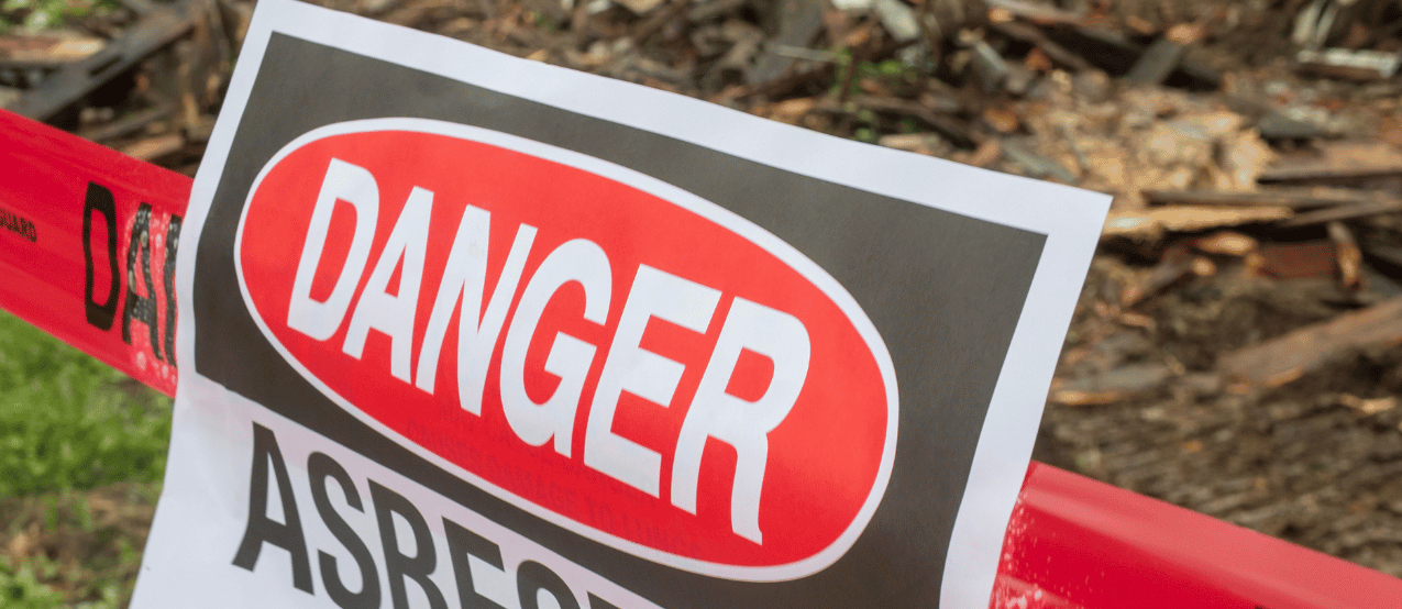 Danger sign and red caution tape blocking access to a wooded area.