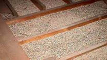 Close-up of beige pebble-textured steps with orange trim on a tiled surface.