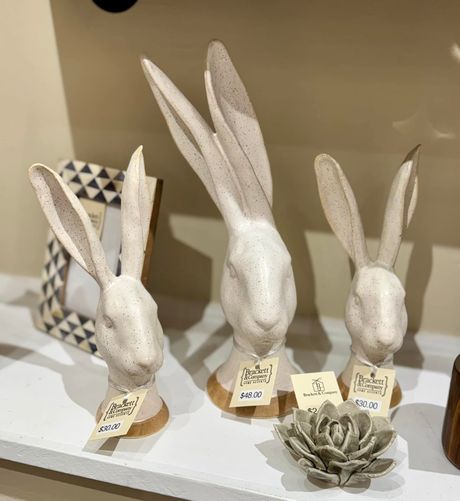 Three white ceramic rabbit figurines on a shelf, with geometric decor and a small succulent