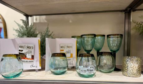 Assorted turquoise glassware and candle holders on a shelf, with white product boxes in the background