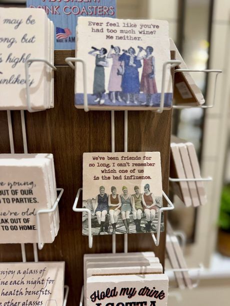 Greeting cards on a wire rack, with illustrated cards and handwritten-style text.