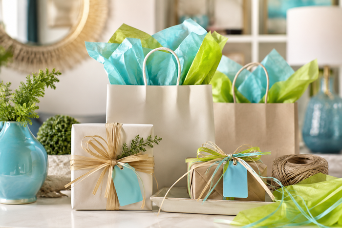 Gift bags and wrapped presents with teal ribbons on a bright tabletop