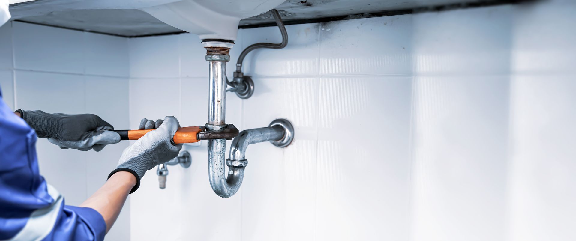 Technician plumber using a wrench to repair a water pipe.