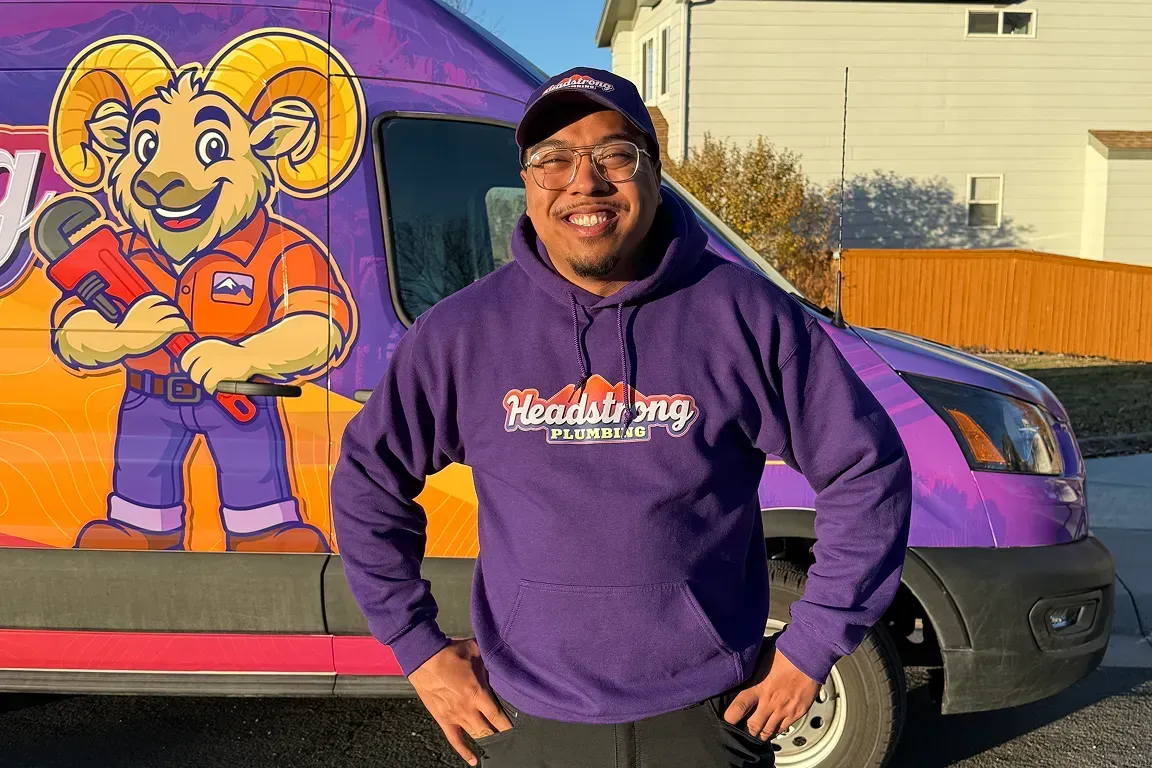 Person in a purple hoodie standing beside a purple van with a cartoon mural.