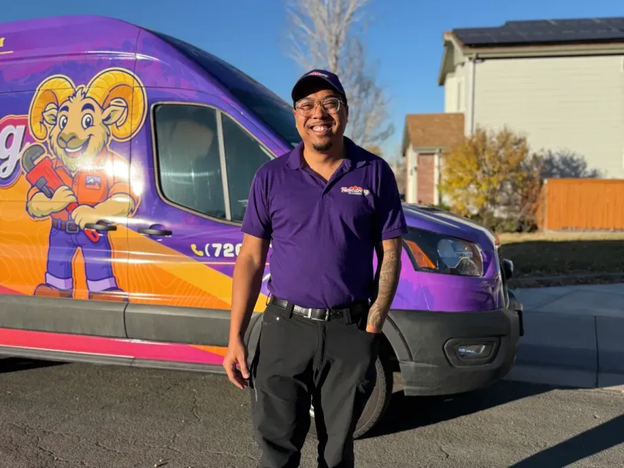 Person in purple shirt standing beside a purple-and-orange van with a cartoon mural.