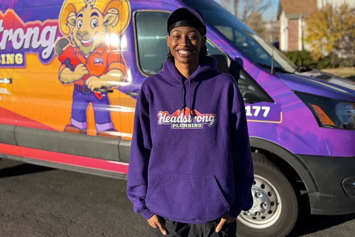 Person in purple hoodie standing in front of a colorful branded van
