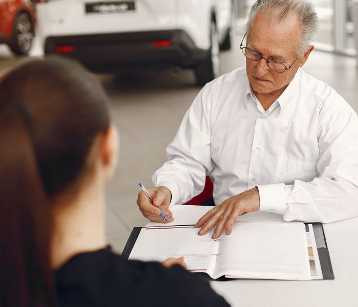A man is sitting at a table signing a document with a woman.