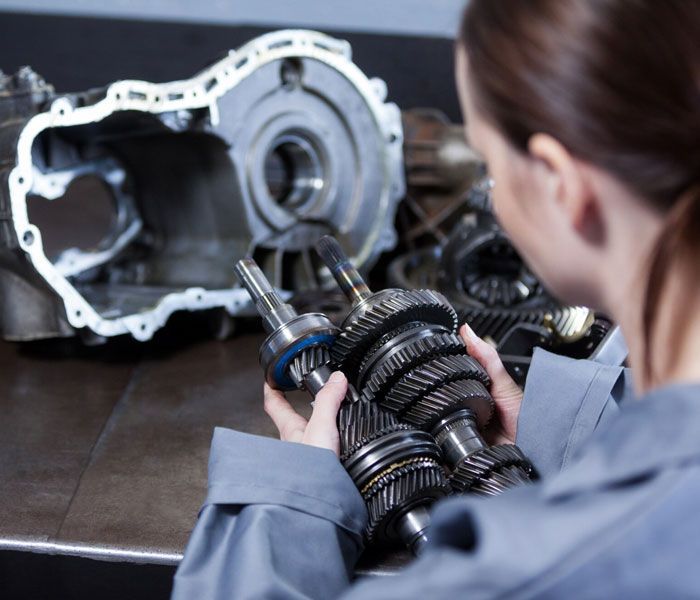 A woman is working on a gearbox in a garage