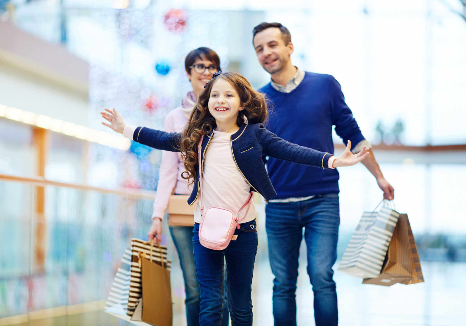 Familie med mor, far, barn der går i shoppingcenter med indkøbsposer