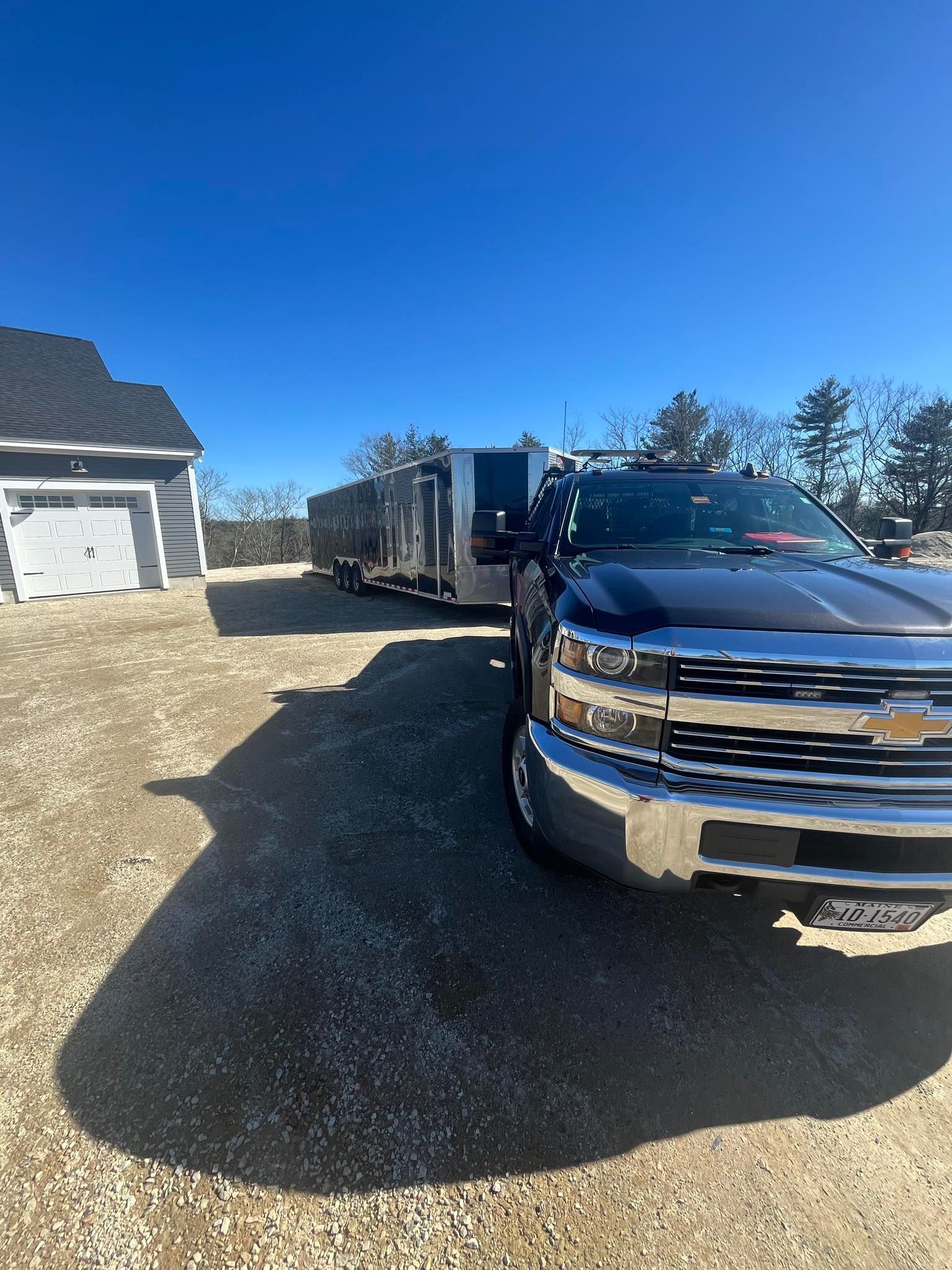 A truck is parked in a gravel driveway next to a trailer.