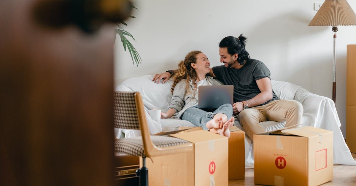 A man and a woman are sitting on a couch using a laptop.