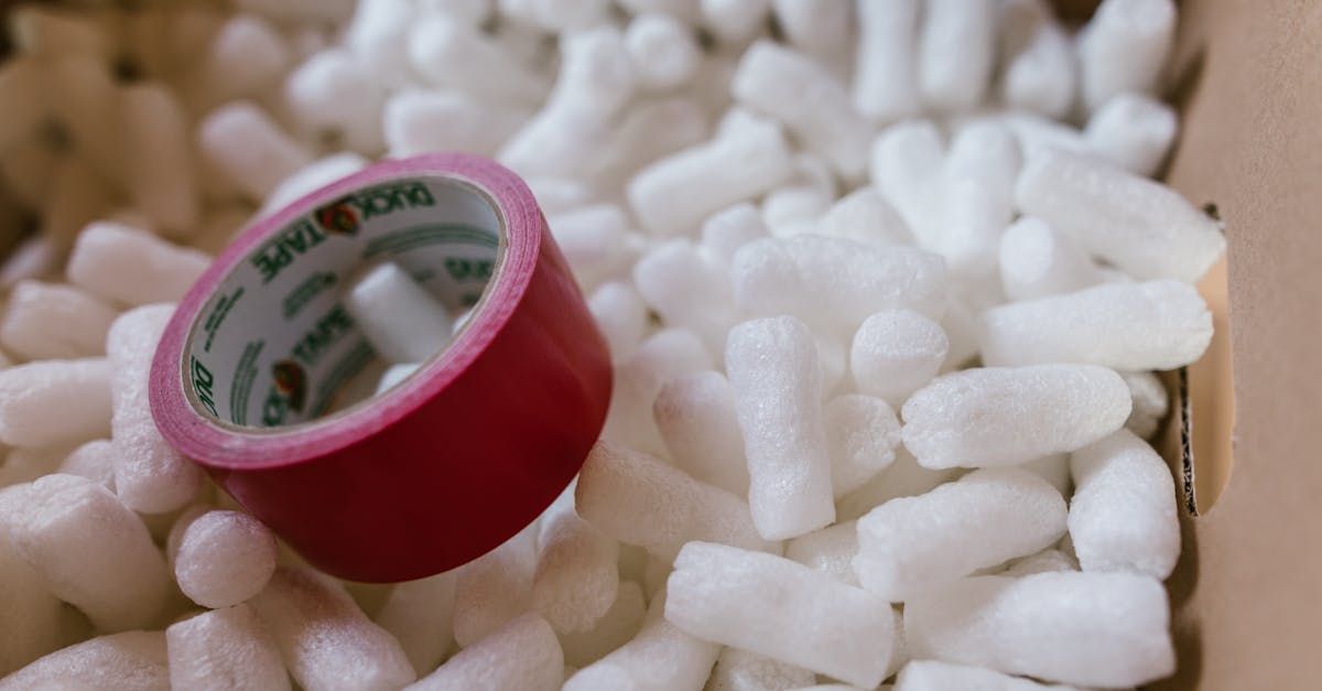 A roll of red tape is sitting on top of a pile of white packing peanuts.
