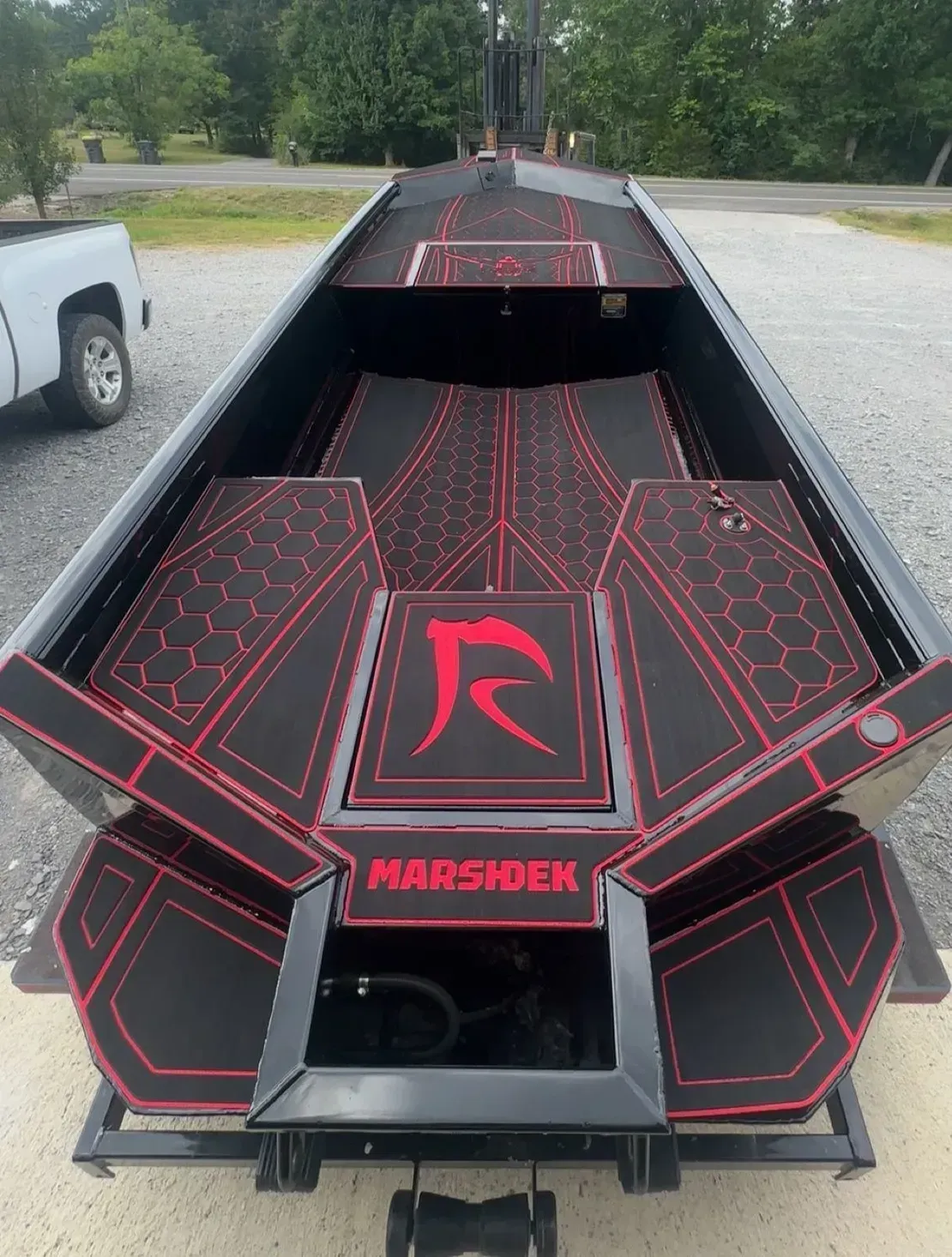 Black-and-red custom boat on a trailer, with geometric graphics and “HARRISEN” on the front.