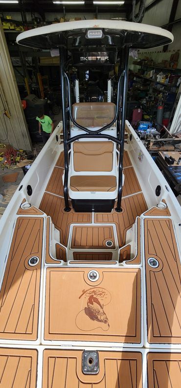 Cockpit view of a boat with a tan deck, black helm chair, and bimini top in a marina