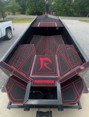 Black and red custom boat on a trailer, viewed from above in a driveway.