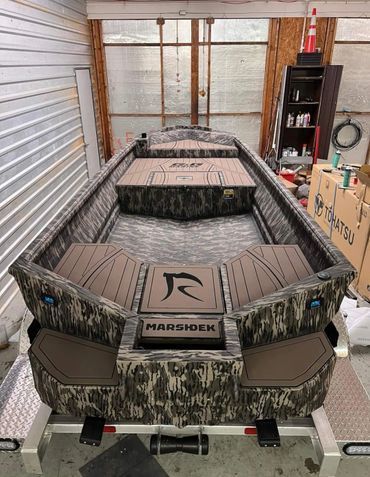 Camouflaged Marsh Tuff boat on a trailer inside a storage garage, viewed from the rear.