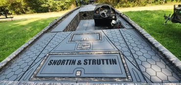 Black-and-gray boat deck with a steering wheel and the name “SNORTIN & STRUTTIN” on the floor panel.