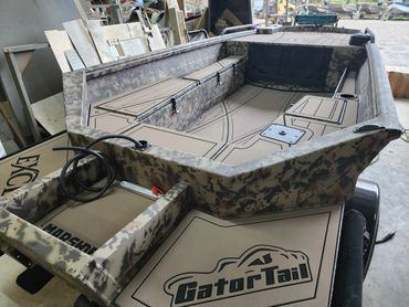 Camouflage-patterned Gator-Tail jon boat interior with black seats and fishing gear in a workshop